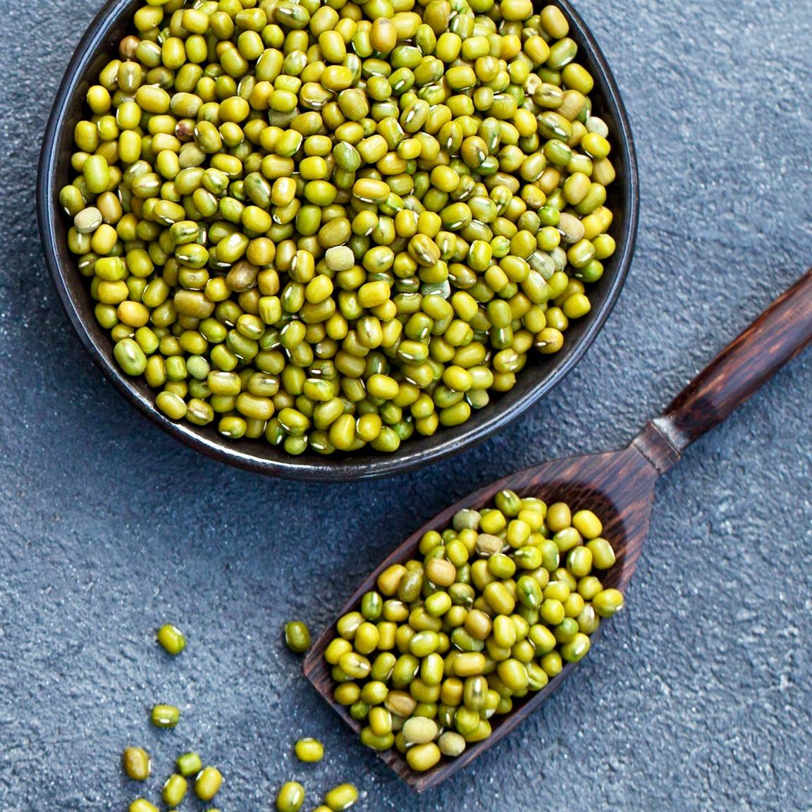 Bowl of raw whole green mung beans and spoon of green mung beans